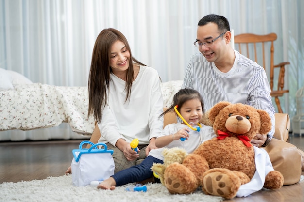 Feliz jovem pai, mãe e uma filha brincando com Toy, sentado no chão na sala de estar, família, paternidade e conceito de pessoas