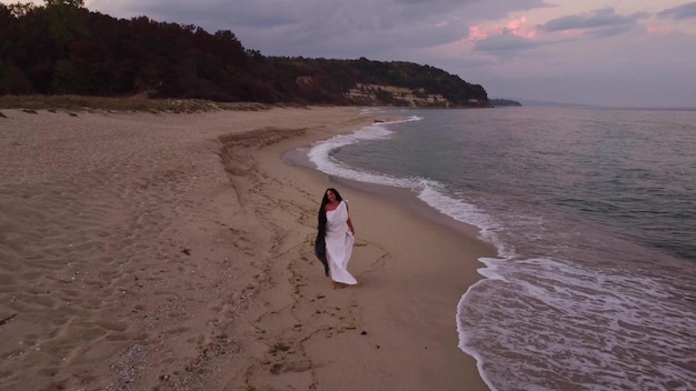 Feliz jovem sensual correndo na praia à noite