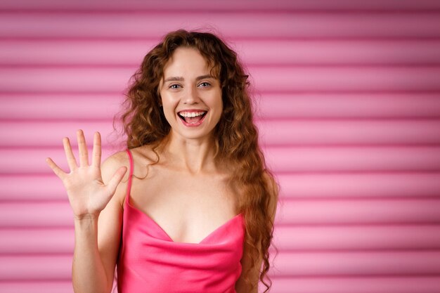 Foto feliz jovem sorridente mostrando cinco dedos e olhando para a câmera