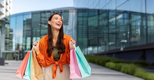 Feliz joven adicta a las compras disfrutando del fin de semana de compras sosteniendo paquetes bolsas y compras al aire libre