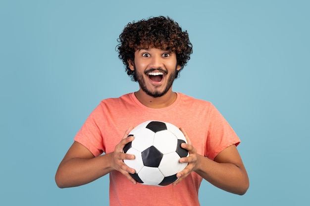 Feliz joven aficionado al fútbol indio posando en azul