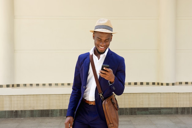 Feliz joven africano con bolsa y teléfono móvil