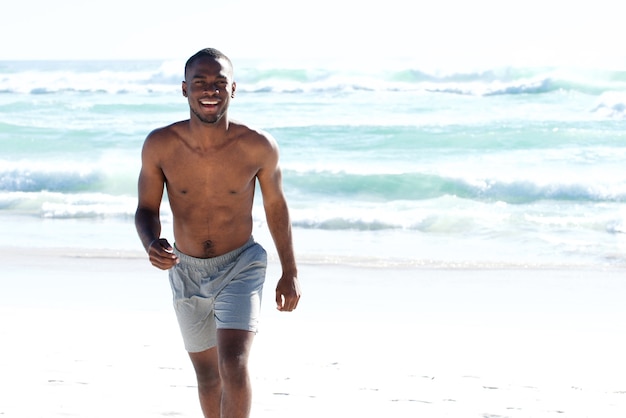 Feliz joven africano caminando en la playa