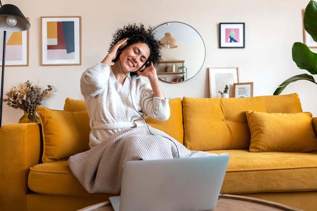 Feliz joven afroamericana bailando en casa sala de estar relajante escuchando música con auriculares Espacio de copia Concepto de estilo de vida