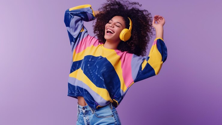 Feliz joven afroamericana bailando escuchando música con auriculares cortados en el fondo