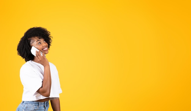 Feliz joven afroamericana rizada llamando por teléfono inteligente hablando con un amigo