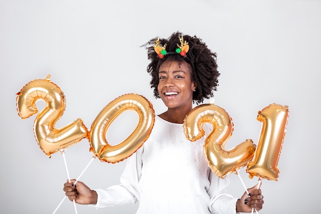 Feliz joven afroamericana sosteniendo 2021 globos de color oro para celebrar