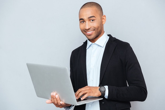 Feliz joven afroamericano sosteniendo y usando laptop