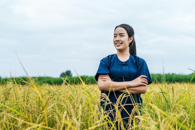 Feliz joven agricultor asiático de pie cruzan sus brazos en el campo de arroz orgánico