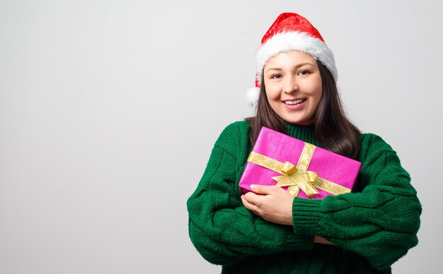 Feliz joven alegre con regalo en manos en gorro de Navidad