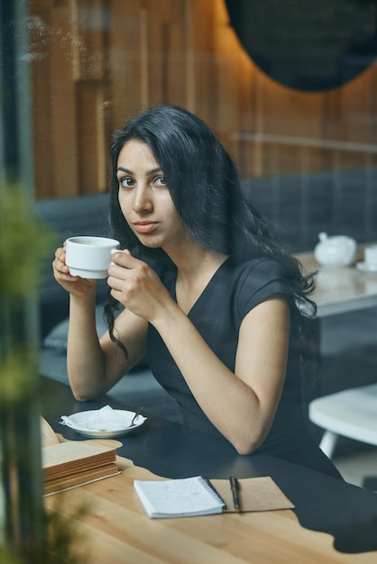 Feliz joven árabe bebiendo café en un café