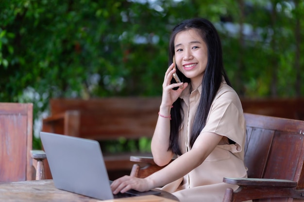 Feliz de joven asiática adolescente estudiante de la universidad hablando haciendo usando teléfono inteligente casual usando portátil