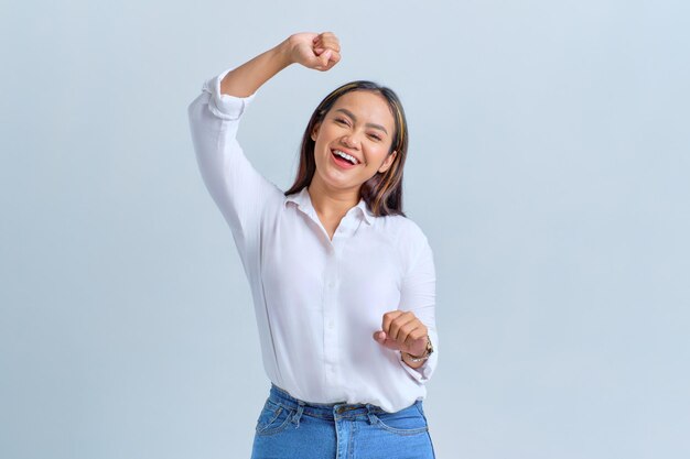 Feliz joven asiática bailando su música favorita olvidándose de todos los problemas aislados sobre fondo blanco