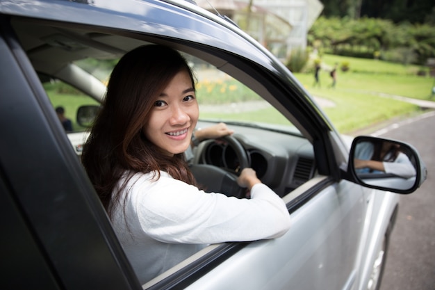 Feliz joven asiática montando un coche