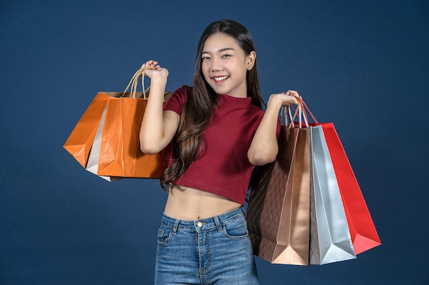 Feliz joven asiática sonriente joven llevando una bolsa de compras coloful