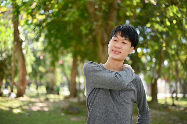 Feliz joven asiático con ropa informal relajándose en el hermoso parque verde el fin de semana