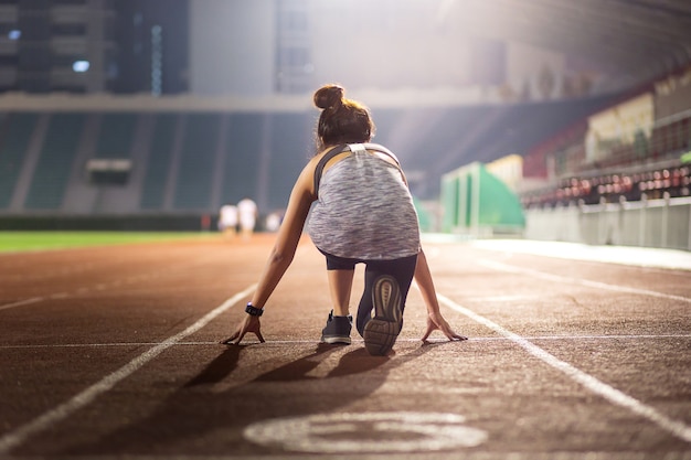 Feliz joven atleta femenina en una posición inicial en el estadio