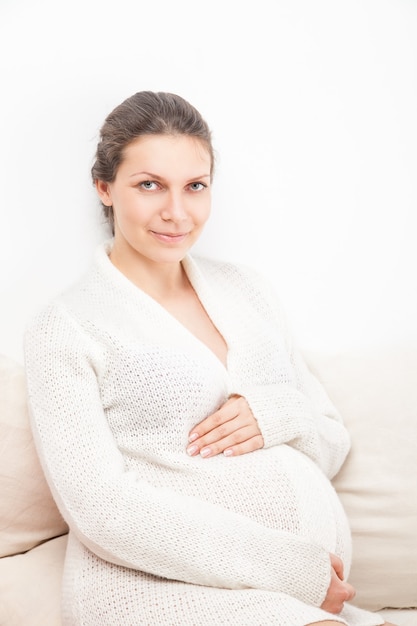 Feliz joven atractiva mujer embarazada con el hermoso vientre sobre fondo blanco.