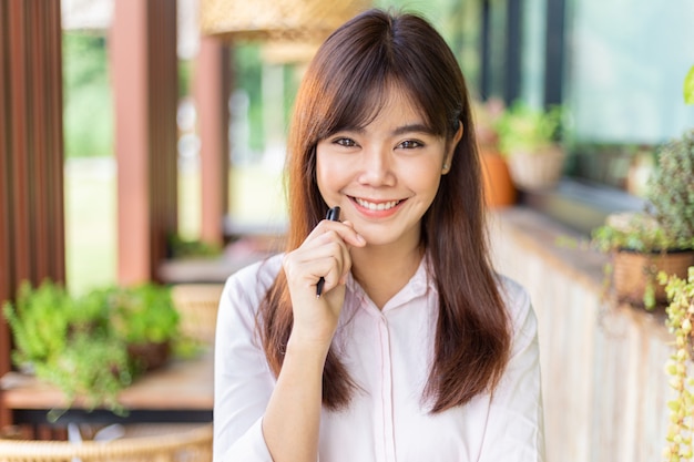 Feliz joven atractiva mujer de negocios asiática sonriendo a la cámara, de pie en el patio al aire libre de su oficina, feliz estilo de vida moderno