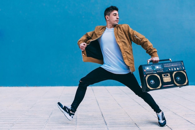 Feliz joven bailando y saltando en la calle con un estéreo de radio vintage xA