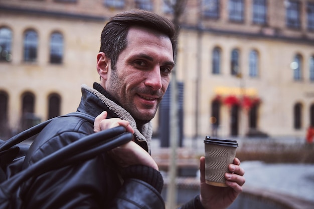 Feliz joven bebiendo café en la calle