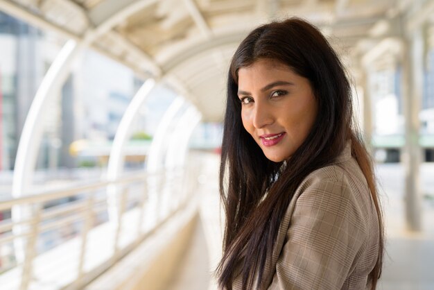 Feliz joven bella empresaria india sonriendo a la pasarela en la ciudad