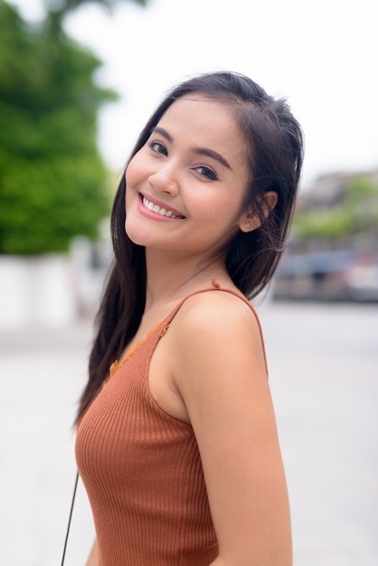 Feliz joven bella mujer asiática sonriendo en las calles al aire libre