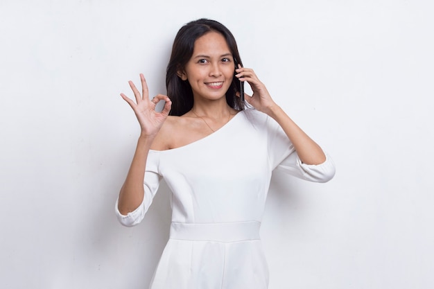 Feliz joven bella mujer asiática mediante teléfono móvil aislado sobre fondo blanco.