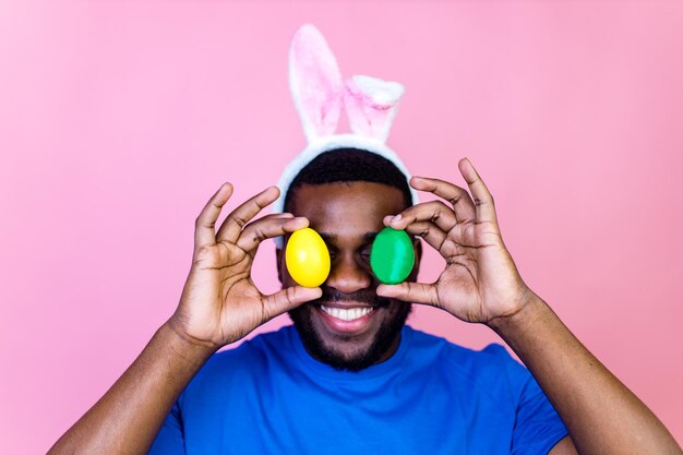 Feliz joven brasilero con orejas de conejo en el fondo de la pared rosa del estudio