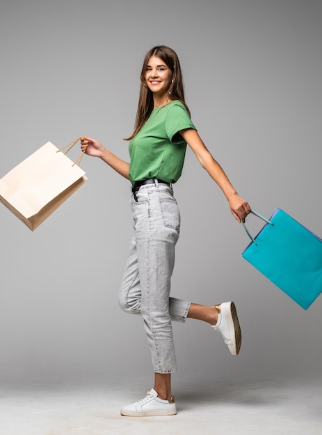 Feliz joven caminando con bolsas de la compra aislado en blanco