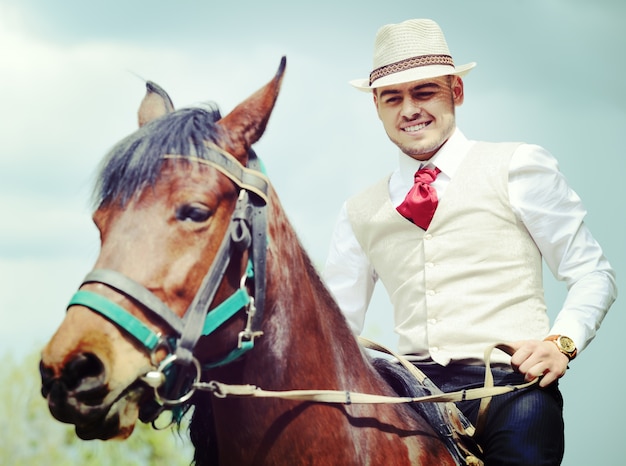 Feliz joven en el campo con caballo para montar