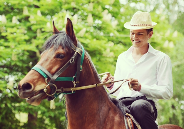 Feliz joven en el campo con caballo para montar