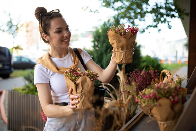 Feliz joven caucásica elige flores en macetas para comprar en el puesto de jardín al aire libre.