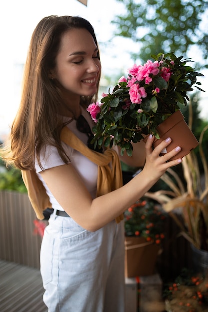 Feliz joven caucásica elige flores en macetas para comprar en el puesto de jardín al aire libre