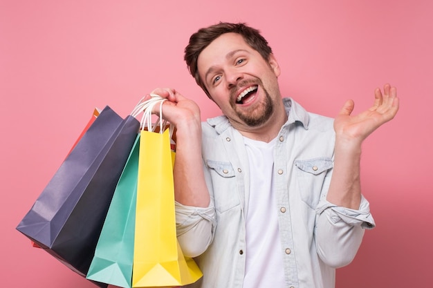 Feliz joven caucásico con bolsas de compras