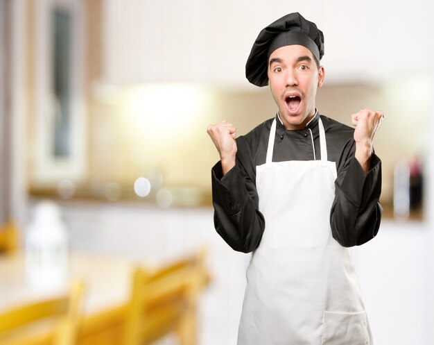 Feliz joven chef con un gesto de celebración