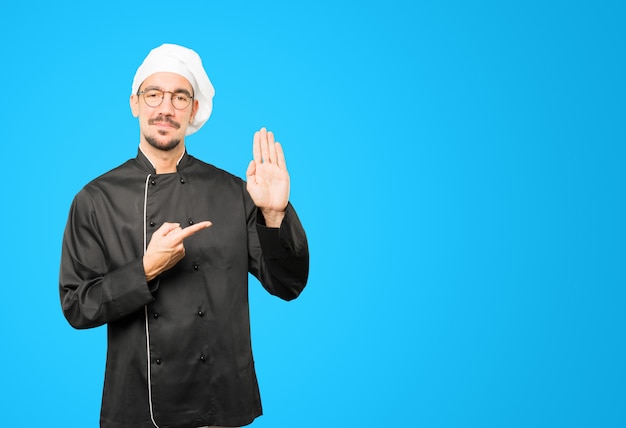 Feliz joven chef haciendo un gesto de parada con la palma de su mano