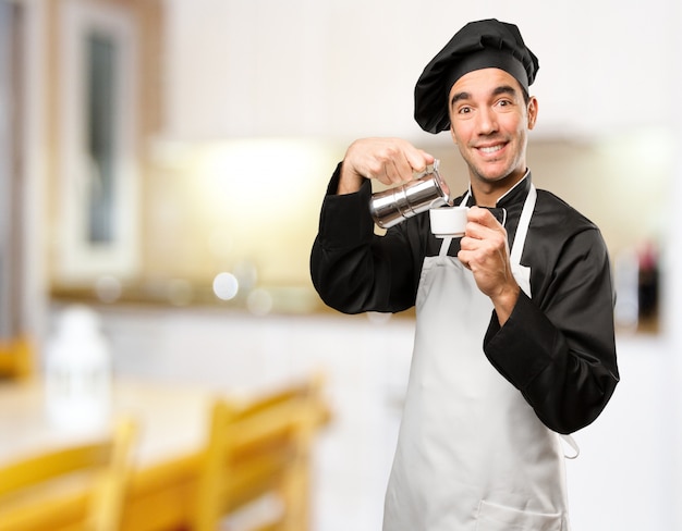 Foto feliz joven chef utilizando una tetera