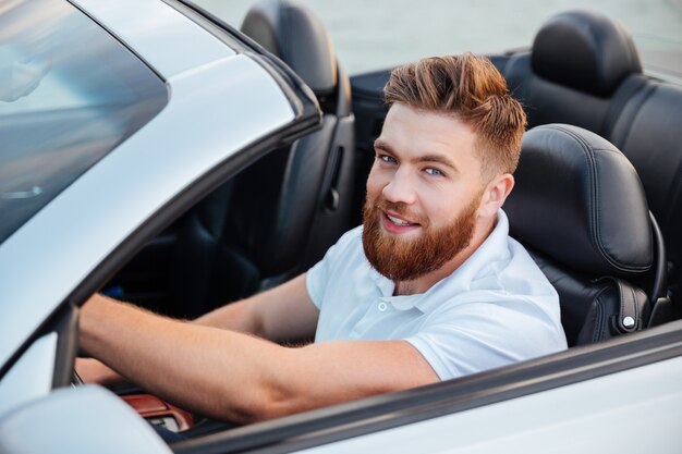 Feliz joven conduciendo cabriolet y mirando al frente