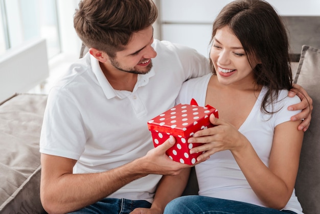 Feliz joven dando presente a su bella novia en casa