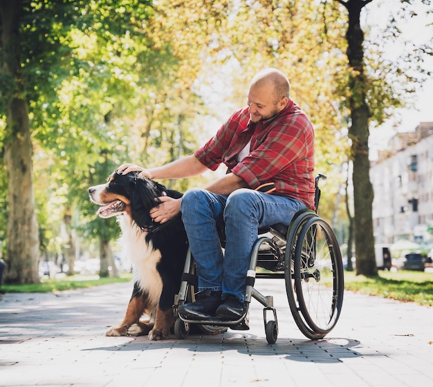 Feliz joven con discapacidad física en silla de ruedas con su perro