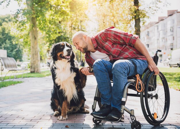 Feliz joven con discapacidad física en silla de ruedas con su perro