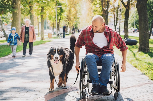 Feliz joven con discapacidad física en silla de ruedas con su perro