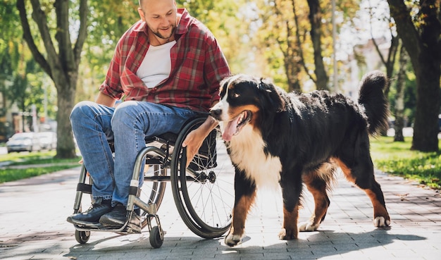 Feliz joven con discapacidad física en silla de ruedas con su perro