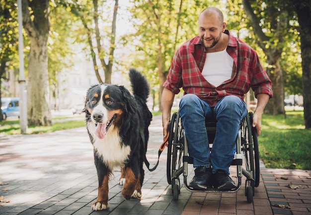 Feliz joven con discapacidad física en silla de ruedas con su perro