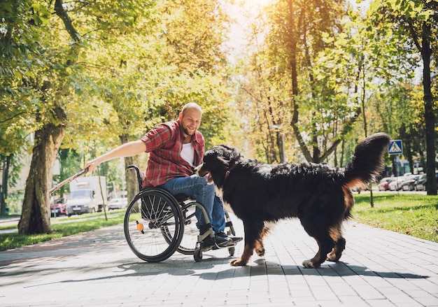 Feliz joven con discapacidad física en silla de ruedas con su perro