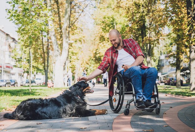 Feliz joven con discapacidad física en silla de ruedas con su perro