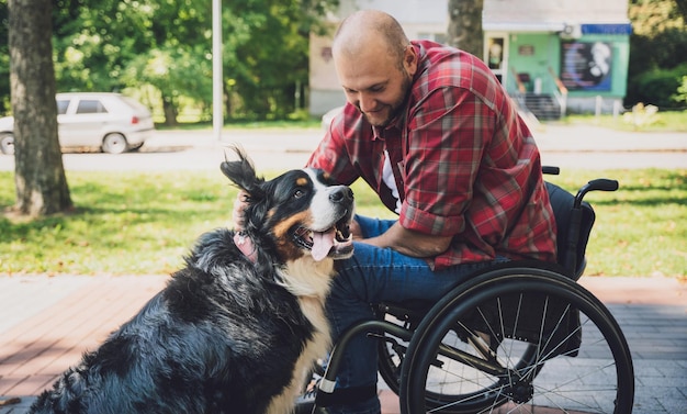 Feliz joven con discapacidad física en silla de ruedas con su perro