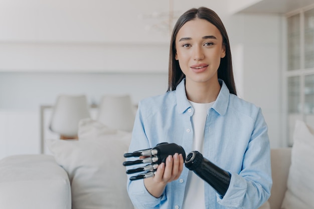 Feliz joven discapacitada está ensamblando prótesis de extremidades biónicas Chica atractiva tiene mano cibernética