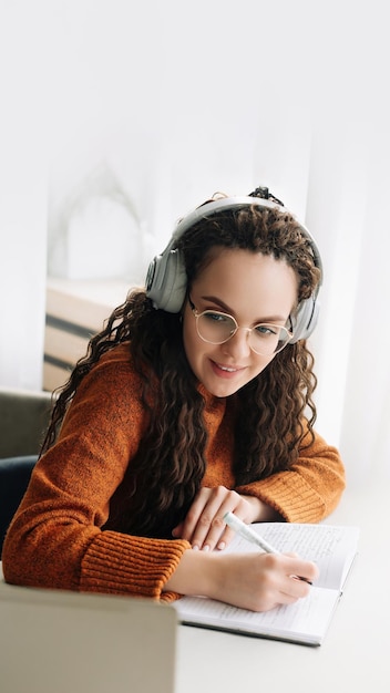 Foto feliz joven elearning en la computadora portátil desde casa asistiendo al seminario web con auriculares estudiante sonriente